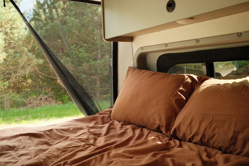  parked on a dirt road near pine trees.|Inside a modern **rv rental**: compact kitchen with sink — photo 3