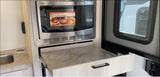 RV rental kitchen showcasing a Speed Cook microwave, pull-out counter, and sink. Compact for travel.