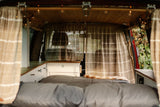 Cozy camper van interior for RV rental, featuring a bed, storage, and ambient lights, perfect for travel adventure.