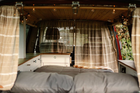 Cozy camper van interior for RV rental, featuring a bed, storage, and ambient lights, perfect for travel adventure.