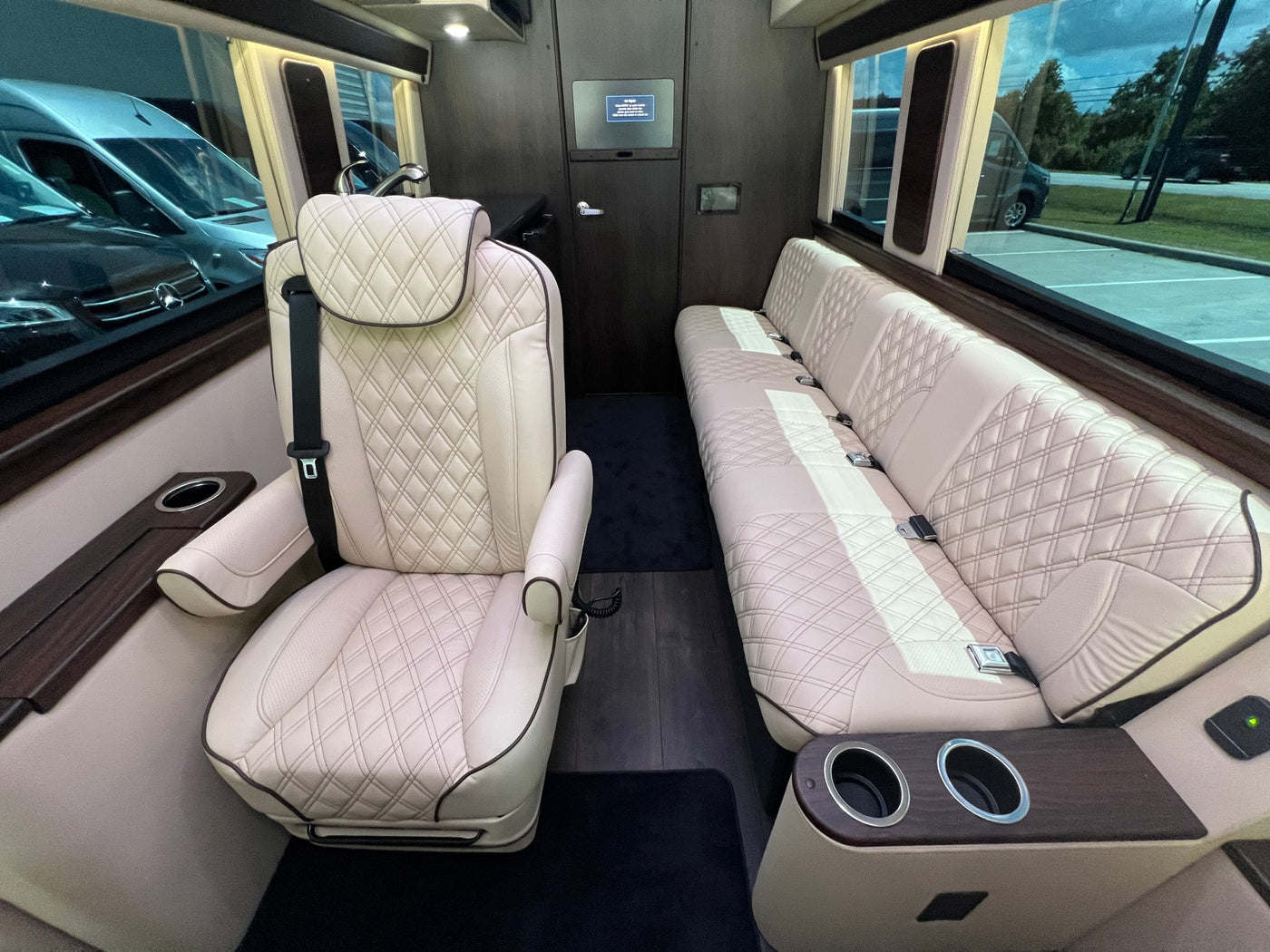 Luxury rv rental interior with plush, quilted leather captain's chair & bench seating, wood accents & cup holders. — photo 6