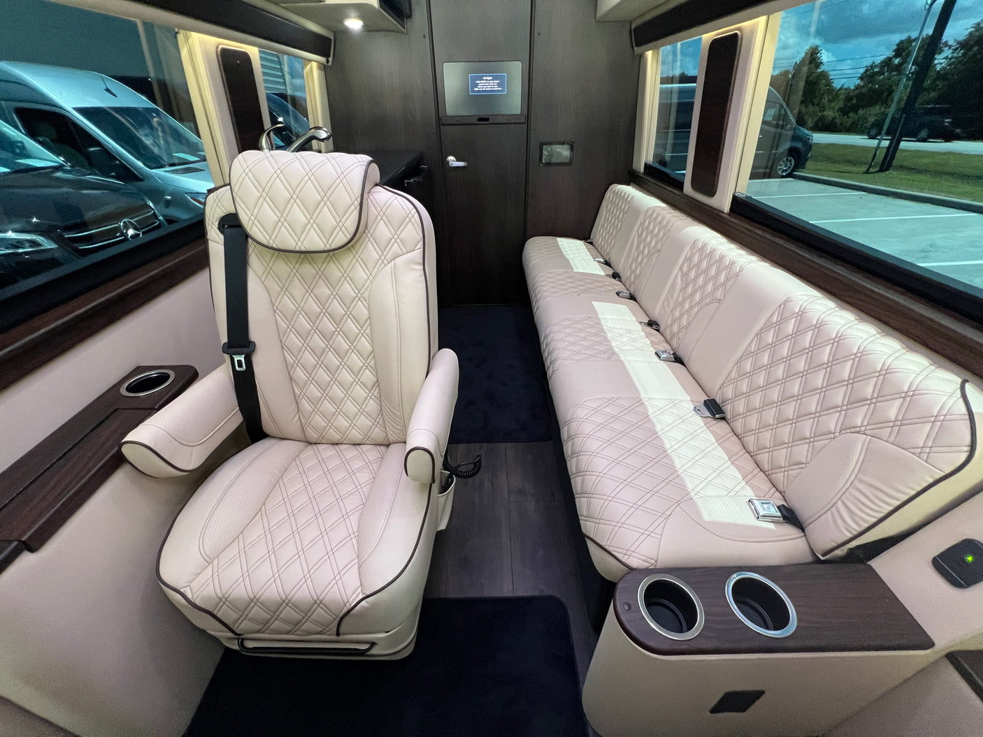Luxury rv rental interior with plush, quilted leather captain's chair & bench seating, wood accents & cup holders.