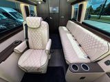 Luxury rv rental interior with plush, quilted leather captain's chair & bench seating, wood accents & cup holders.