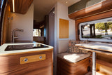 Modern RV rental interior with a well-equipped kitchen, comfortable seating, and dining area, visible through a large window.