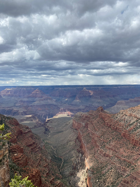 Panoramic Grand Canyon view with towering red rock formations under a cloudy sky. Explore this natural wonder by RV rental.