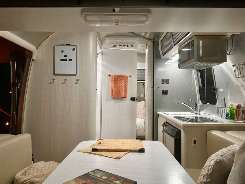 Cozy RV rental interior features a kitchenette, dining area, and bedroom access, ideal for mobile home adventures. — photo 13