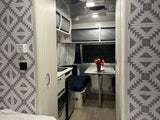 Modern RV rental interior with kitchen, dining area, and stylish geometric wall accents. Ideal for travel trailer adventures.
