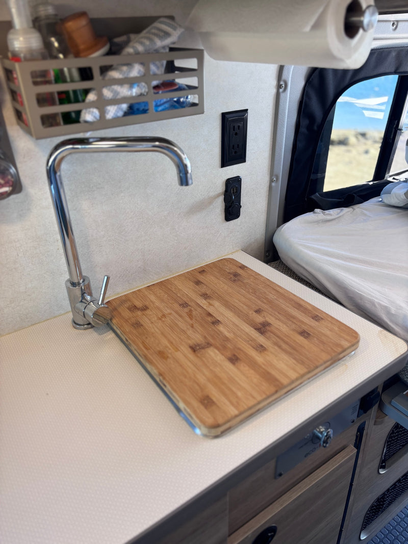Experience an RV rental with a functional kitchen area including a sink, cutting board, outlets, and cozy sleeping space. — photo 20