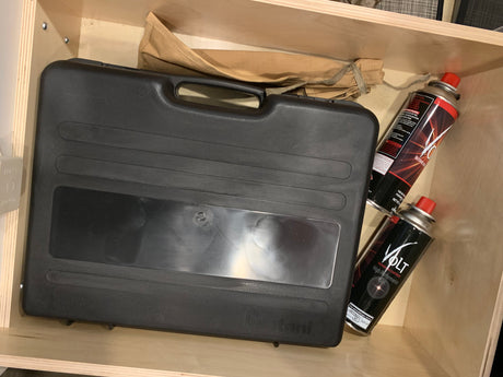 Iwatani portable stove case & Volt butane gas in an RV rental drawer. Essential for camping meals.