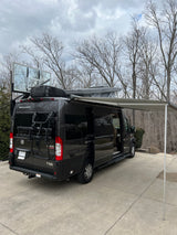 Black rv rental camper van with extended awning, roof-top tent, bike rack, and a unique basketball backboard attachment.