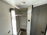 RV rental interior: open storage cabinet, entry door, & interior door. Ceiling smoke detector & wall thermostat visible.
