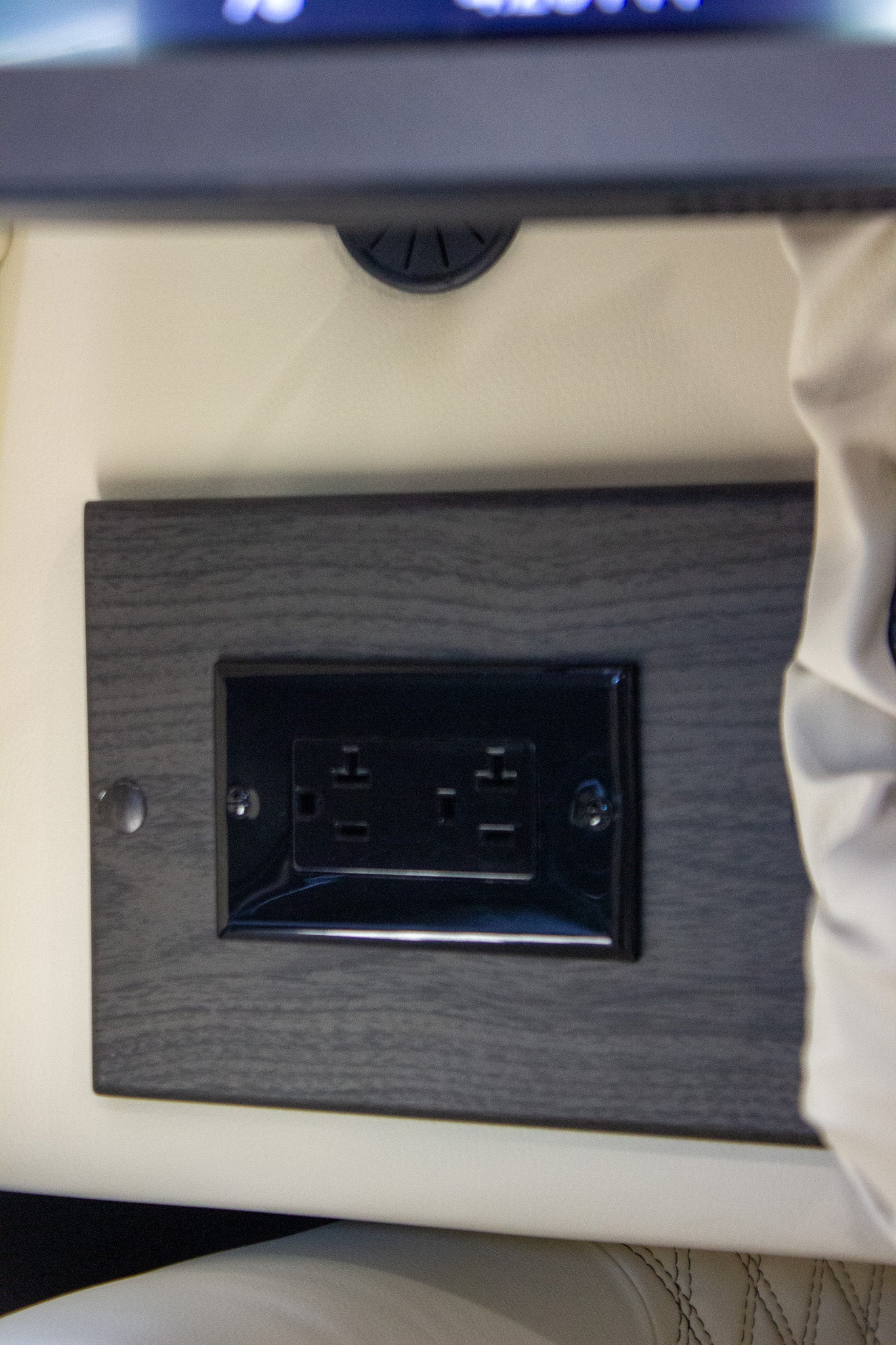 RV rental dual electrical outlets mounted on a dark wood-textured panel, offering convenient power in the interior.
