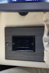 RV rental dual electrical outlets mounted on a dark wood-textured panel, offering convenient power in the interior.