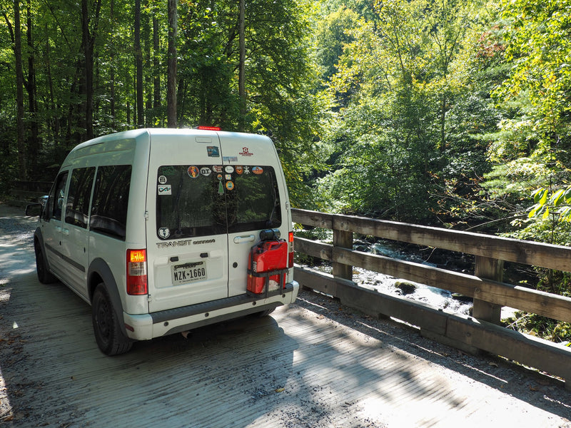 RV rental: Ford Transit Connect campervan on a scenic bridge over a stream in a lush forest, ideal for van life. — photo 1