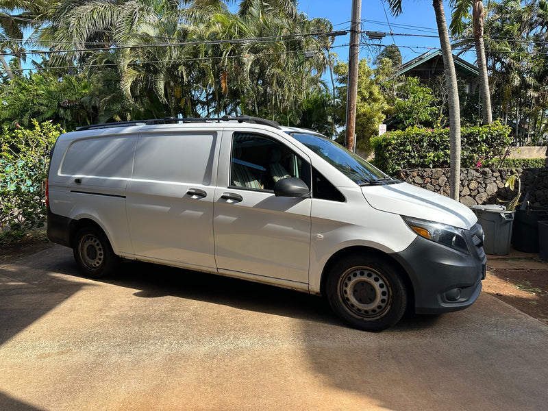 A white panel van, often sought for rv rental conversions, parked on a sunlit driveway in a lush tropical setting. — photo 4
