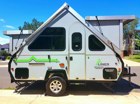 Gray A-frame pop-up travel trailer for rv rental. Its distinctive triangular roof and windows are visible.