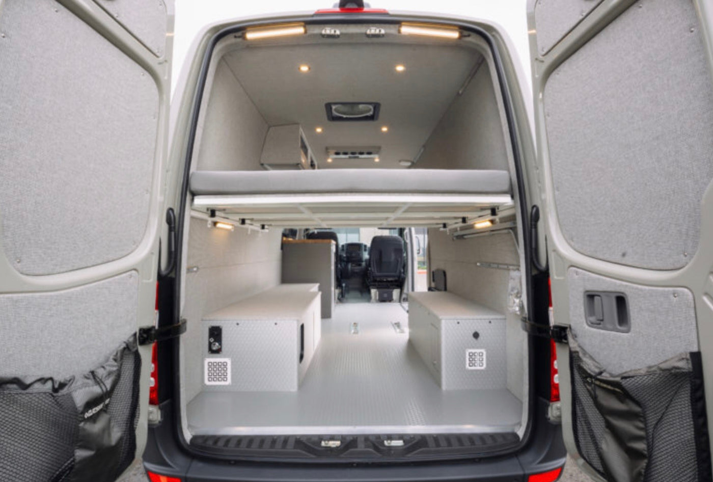 RV rental van conversion: open rear view showing elevated bed, storage boxes, and well-lit interior. — photo 3