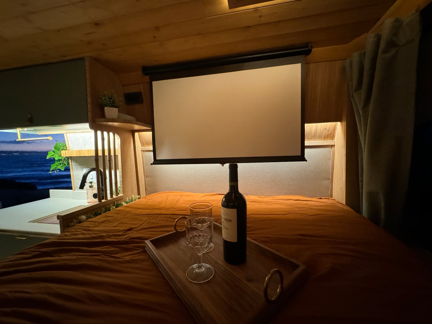 Experience luxury travel! This rv rental offers a projector screen, wine, and ocean views from a cozy bed.