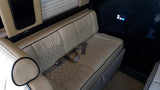 RV rental interior: luxurious beige leather bench seating with quilted patterns, seatbelts, and a lit control panel.