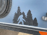 An RV rental side panel features a Sasquatch and forest decal. The dusty blue surface suggests exciting outdoor adventures.
