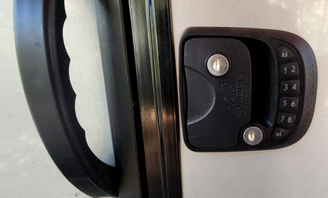 RV rental door with black handle & RVLOCK keyless keypad for secure entry. Two keyholes visible.