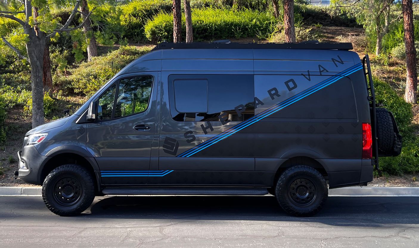 Dark gray Mercedes Sprinter adventure van, branded 'SHEPARDVAN', with off-road tires and blue stripes, an RV rental option.