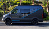 Dark gray Mercedes Sprinter adventure van, branded 'SHEPARDVAN', with off-road tires and blue stripes, an RV rental option.