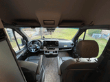 Spacious RV rental cockpit with Mercedes-Benz steering wheel, comfortable front seats, and a clear view out the windshield.