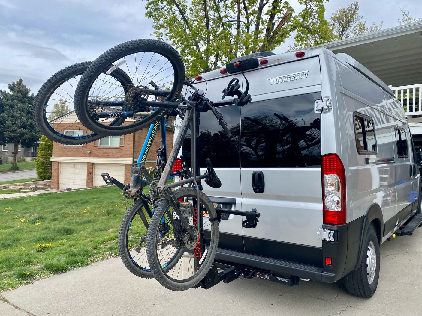 A silver Winnebago RV rental transports two mountain bikes on a rear hitch rack, ready for outdoor adventures.
