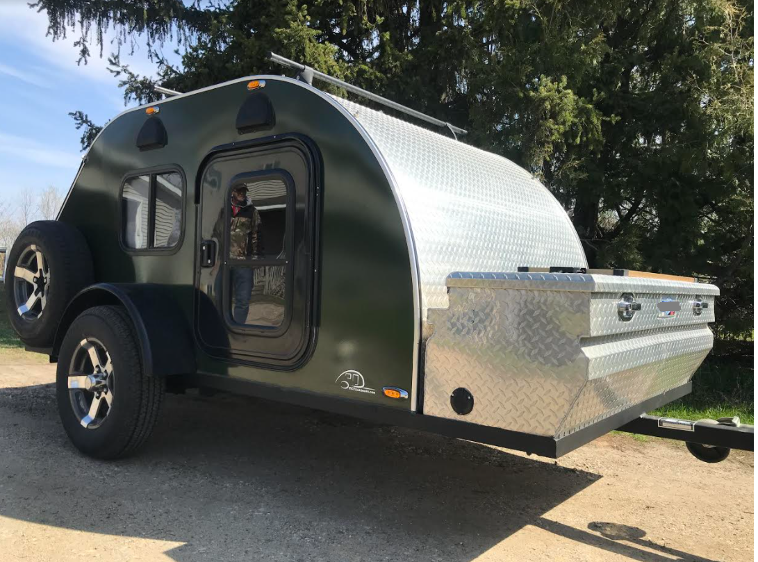 This dark green teardrop camper trailer, featuring diamond plate details, is ready for your next RV rental adventure.