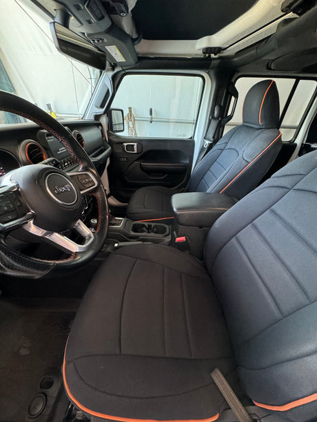 Inside a Jeep: black/orange custom seats, steering wheel, and dash visible. Consider this robust option for your rv rental needs.
