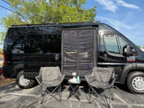 This black Ram ProMaster RV rental is set up for relaxation with a side screen and comfy chairs.