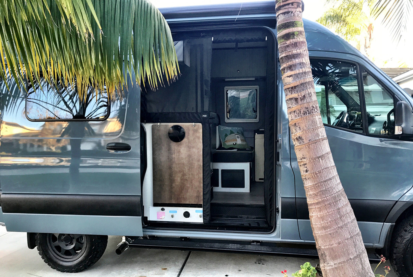 Blue-grey camper van rv rental with open side door, revealing its compact, functional interior. Ready for mobile adventures!