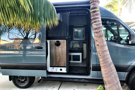 Blue-grey camper van rv rental with open side door, revealing its compact, functional interior. Ready for mobile adventures!