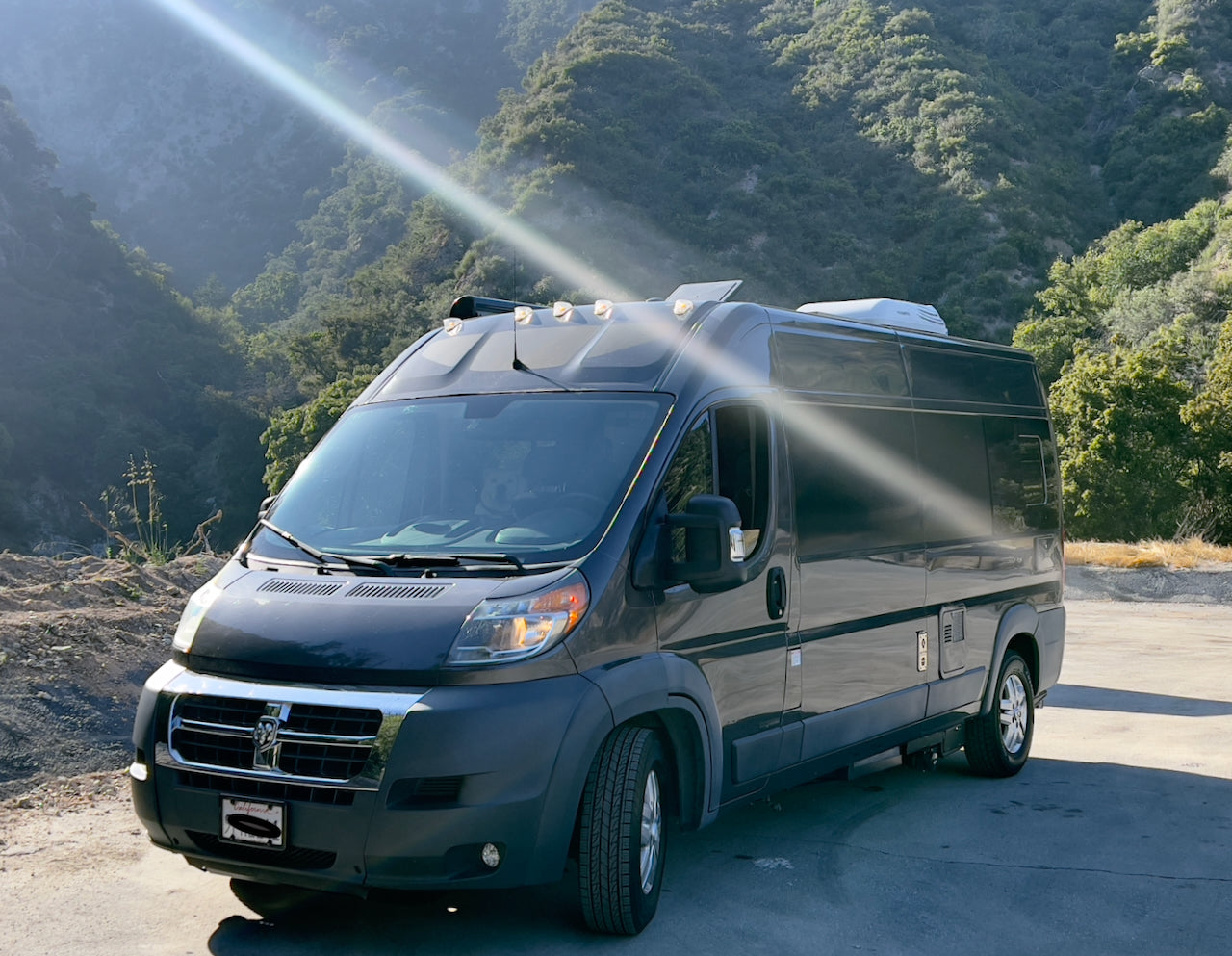 Dark grey camper van parked outdoors, perfect for an RV rental. Explore scenic mountains with this versatile travel vehicle.