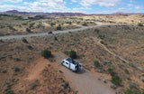 White rv rental camper van with solar panels parked in a scenic desert landscape with mountains and dogs.