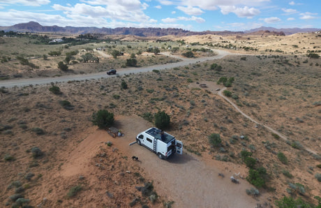 White rv rental camper van with solar panels parked in a scenic desert landscape with mountains and dogs.