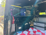Inside an organized RV rental, packed with adventure gear, storage totes, and a portable cooler for travel comfort.