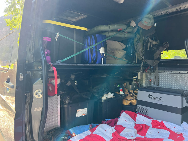Inside an organized RV rental, packed with adventure gear, storage totes, and a portable cooler for travel comfort. — photo 3