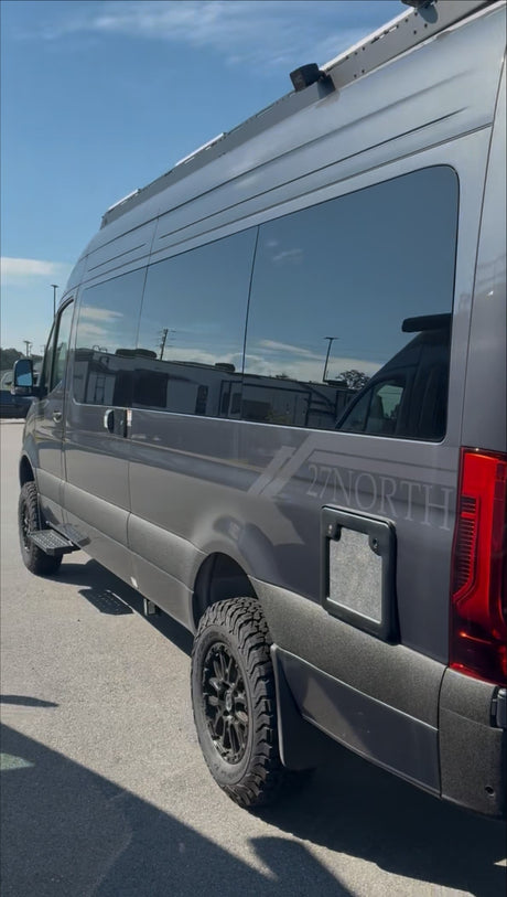 Sleek gray adventure van with "27 NORTH" branding & off-road tires. Ideal RV rental for outdoor exploration.