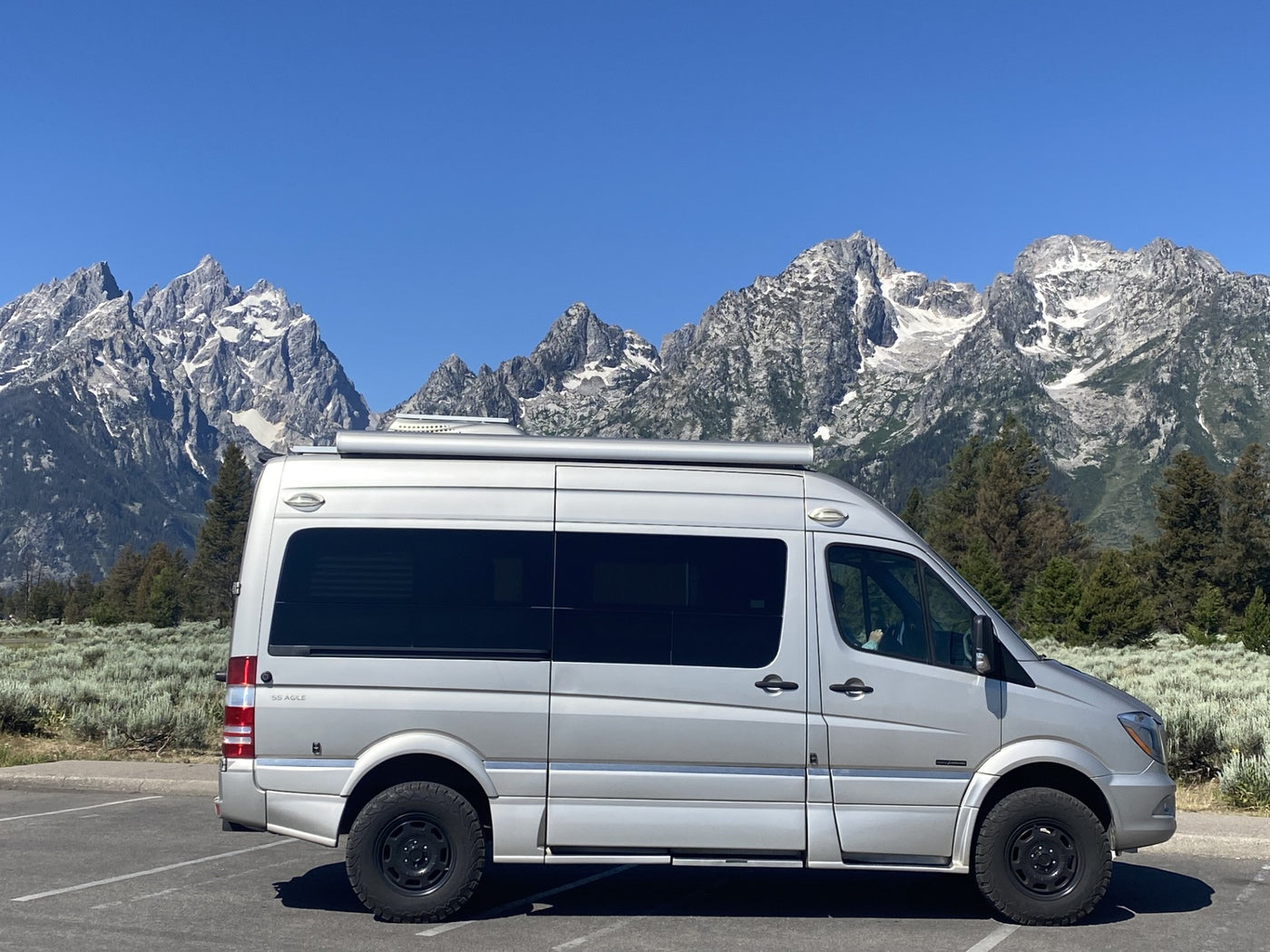  and chair are visible.|This silver Roadtrek SS Agile camper van is perfect for an RV rental adventure exploring stunning rocky landscapes at dusk.|RV rental interior looking forward: Kitchenette — photo 15