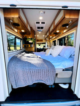 Experience comfort on the road! This RV rental offers a well-appointed interior with a cozy bed and scenic views.