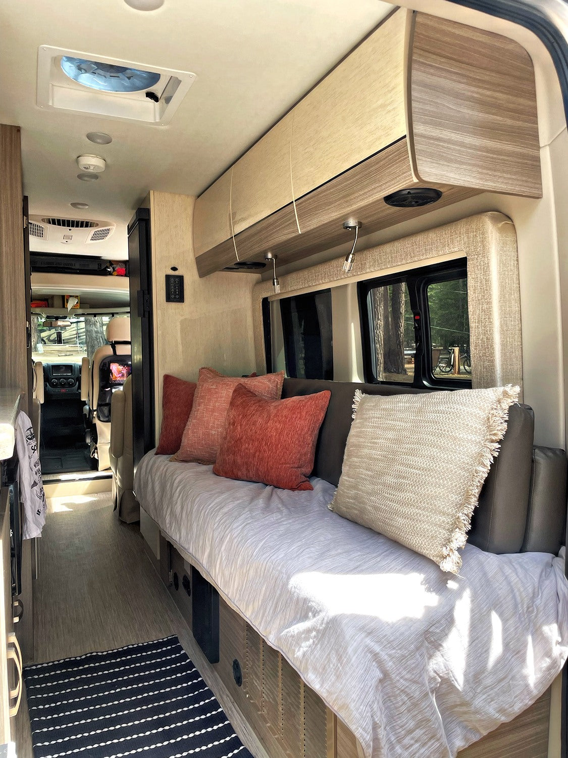 Inside a modern RV rental, featuring a cozy sofa/bed, overhead storage, and a well-lit living area, perfect for adventure.