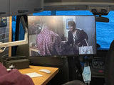 Inside an RV rental: a mobile workspace with a large screen for entertainment, overlooking calming blue water.