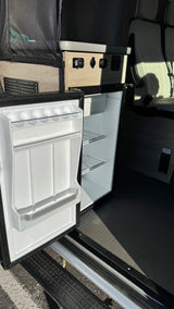 This RV rental features a convenient, open mini-fridge, visible power outlets, and comfortable seating for your road trip comfort.