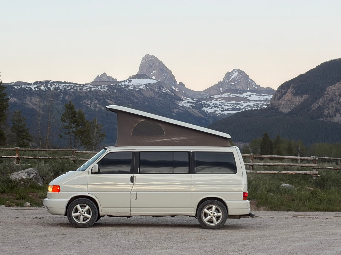 Experience vanlife with this RV rental! White pop-top camper van parked with majestic, snow-capped Grand Teton mountains behind. — photo 1