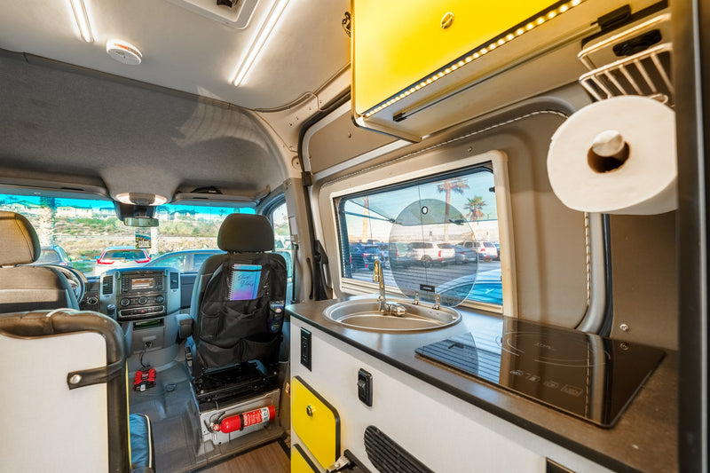 This RV rental's cozy interior features a compact kitchen with sink and cooktop, front cabin, and a fire extinguisher for safety. — photo 20