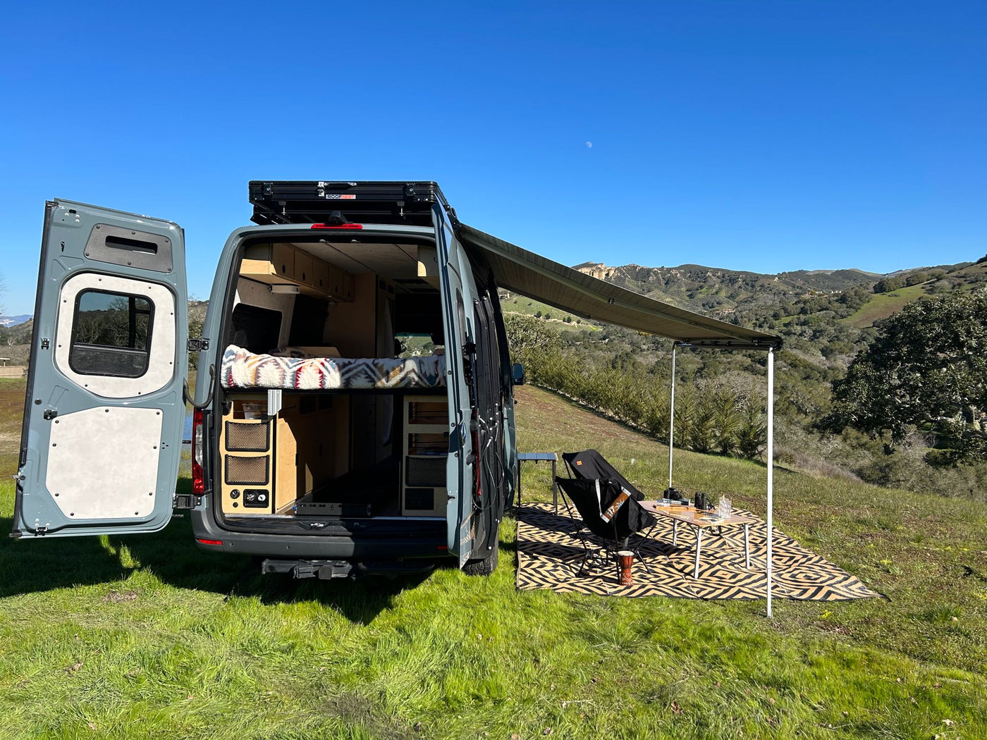  shows a cozy bed & convenient pull-out storage.|This RV rental offers a functional interior with swivel chairs — photo 10