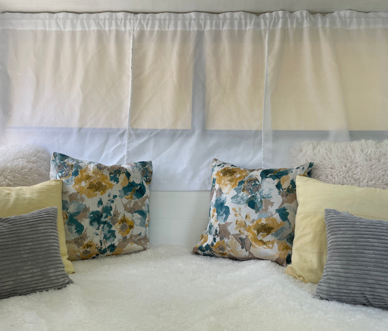 Cozy RV rental nook. Sheer curtains, plush white base, colorful floral, yellow, and grey pillows for comfort. — photo 10