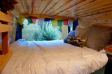 Experience comfort in this RV rental's cozy bed. Wood-paneled interior, prayer flags, and a desert view awaits.